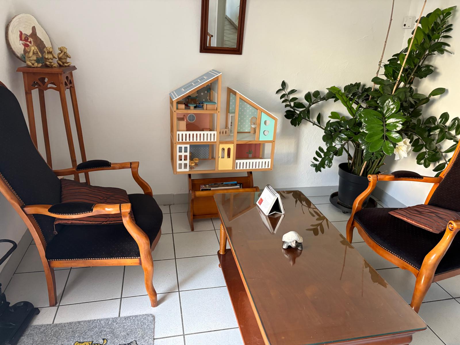 Pièce du cabinet avec fauteuils, table et maison de poupée.